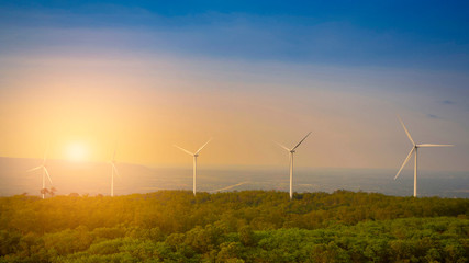 Fototapeta na wymiar wind turbine or windmill is alternative energy and green technology with beautiful sunset sky and tree on a the mountain and landscaping shot photo, with copy space.