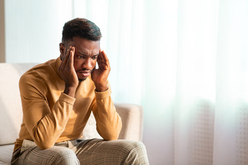 African American Man Suffering From Headache Sitting At Home