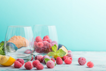 frozen berries in glass on blue color background