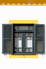 White building exterior with green window and shutters and yellow trim
