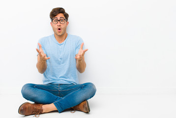 young handsome man feeling extremely shocked and surprised, anxious and panicking, with a stressed...