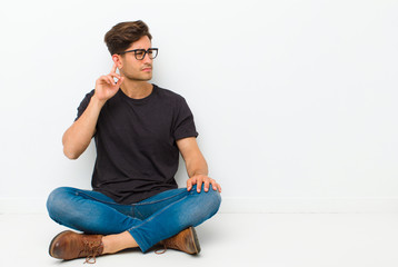 young handsome man looking serious and curious, listening, trying to hear a secret conversation or...