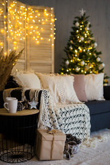Christmas background - cozy interior with decorated  Christmas tree, sofa and folding screen with garlands