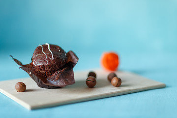 muffin and macadamia nuts on a wooden tray on a blue background