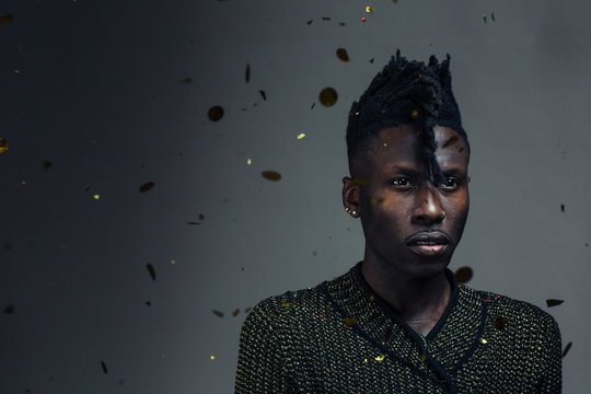 Portrait Of A Young Man With Cool Hair And Confetti Falling, On Dark Black Studio Background