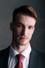 Young man in a black suit on a dark background