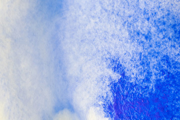 A stain of blue watercolor paint on paper dipped in water. Macro photo. Background minimalistic vibrant image. The concept of drawing...