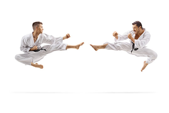 Two young men with black belts in karate jumping in air with a kick