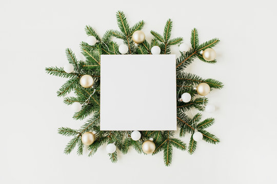Christmas, New Year composition. Square blank frame with copy space, fir branches, Christmas baubles on white background. Flat lay, top view festive holiday mockup.