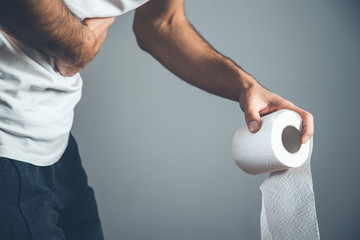 man holding a roll of toilet paper on gray background
