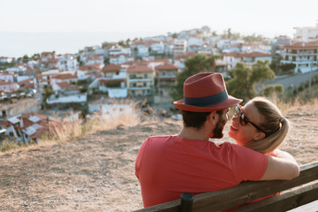 Fototapeta premium Young couple in love enjoying the view of the town and sunset from a hill in Greece