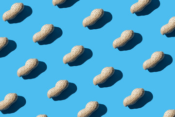 Pattern of peanuts on a blue background. Flat lay. Minimal background texture of food nut. Creative layout