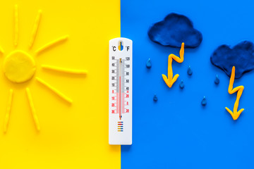 Weather forecast concept. Sun, rain and thermoneter on yellow and blue background top view copy space - obrazy, fototapety, plakaty