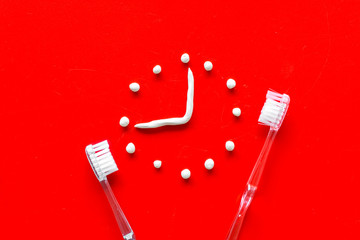 Time to brushing teeth. Watches near teethbrushing on red background top view copy space