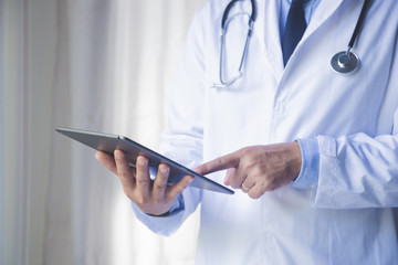 Doctor man using tablet computer for network research or virtual disease treatment, hands close-up. medic data and healthcare concept.