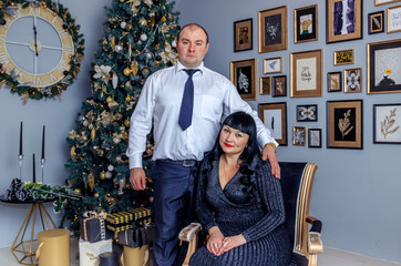 Husband and wife are sitting under the New Year tree. Christmas family. New Year holiday. Dressed up Christmas tree.