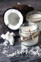 Jars of coconut milk, coconut flakes, coconut. Coconut milk extraction. Vegan milk. Selective focus. Macro.
