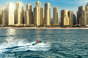 man bashing the waves on the sea with dubay skyline in the background