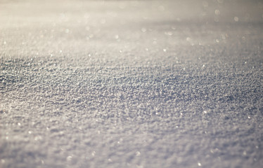 Snowy white background. The texture of the snow. Shiny snow with bokeh and blurred background close-up. White snow-covered field. Macro photo of snow.