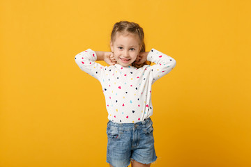 Little cute child kid baby girl 4-5 years old wearing light denim clothes isolated on pastel yellow...