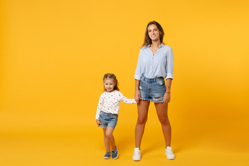 Woman in light clothes have fun with cute child baby girl 4-5 years old. Mommy little kid daughter isolated on yellow background studio portrait. Mother's Day love family parenthood childhood concept.