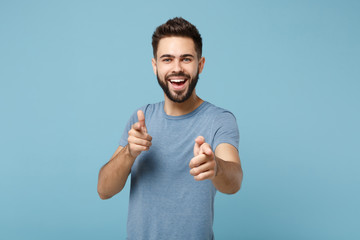 Young cheerful handsome man in casual clothes posing isolated on blue wall background, studio...