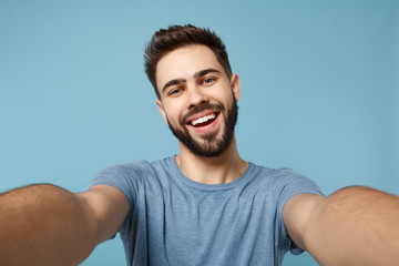 Close up Young joyful man in casual clothes posing isolated on blue wall background studio portrait. People sincere emotions lifestyle concept. Mock up copy space. Doing selfie shot on mobile phone.