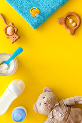 Baby food background with toys and accessories on yellow table top view pattern frame space for text