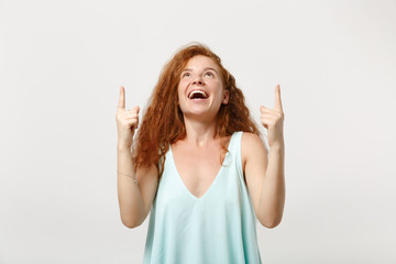 Fototapeta na wymiar Young cheerful excited redhead woman girl in casual light clothes posing isolated on white wall background, studio portrait. People lifestyle concept. Mock up copy space. Pointing index fingers up.