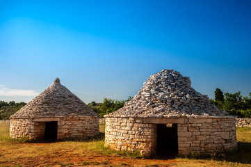 Three traditional istrian huts - Kazun, with blue sky in background.