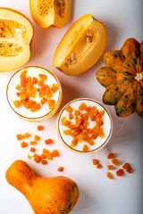 Pumpkin raw dessert. Pumpkin smoothie with yogurt and dried apricots in glasses on a white background. Autumn healthy homemade diet food. Top view.