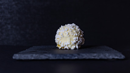 white truffle-shaped chocolate dessert on a black background