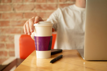 guy with coffee cup and laptop in cafe