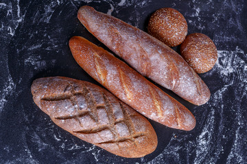 Bakery - gold rustic crusty loaves of bread and buns on black chalkboard background.