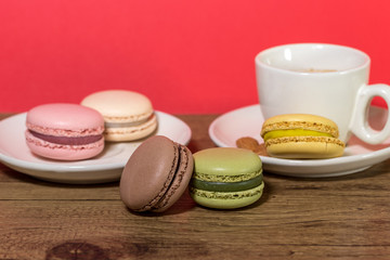 multicolor macarons on a wooden rustic table and red background