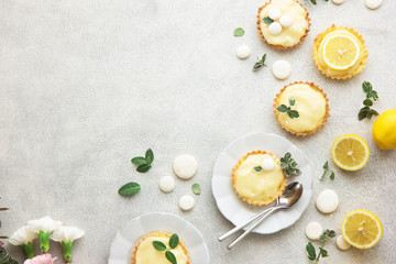 french desserts - tarts with lemon custard cream filling topped with  fresh mint on a concrete table, empty space, flatlay - obrazy, fototapety, plakaty
