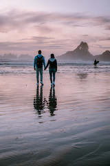 Tofino Vancouver Island, sunset at cox bay with surfers by the ocean during fall season Canada,...