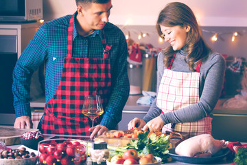 Couple celebrating Christmas in the kitchen cooking christmas duck or Goose