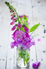 Purple flowers in a glass vase on gray wooden background