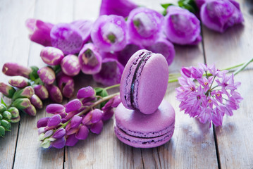 Purple flowers and macaroon on a wooden background