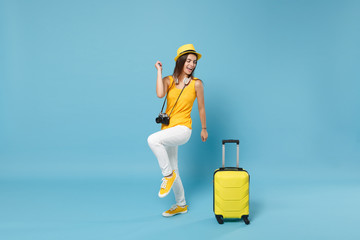 Traveler tourist woman in yellow casual clothes, hat with suitcase photo camera isolated on blue...