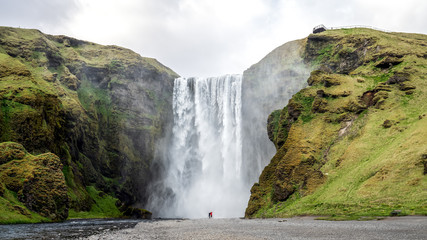Huge waterfall of Skogafoss with a couple taking photographs, Skogar, south of Iceland