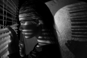 poster style Portrait of young woman looking through  sun blinds window shutter artistic version 