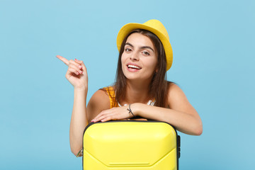 Traveler tourist woman in yellow casual clothes, hat with suitcase photo camera isolated on blue...