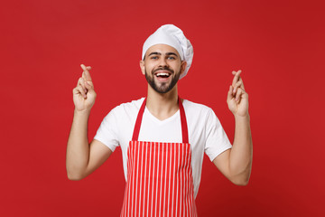 Young male chef cook or baker man in striped apron toque chefs hat isolated on red background....