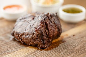 Fried dry aged beef fillet chateaubriand medallion steak natural with Pickled cabbage and two sauces. Serving on a wooden Board. Barbecue restaurant menu.