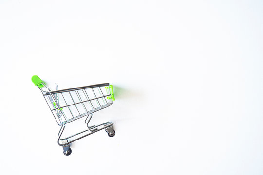 Empty green miniature shopping cart isolated on white background.