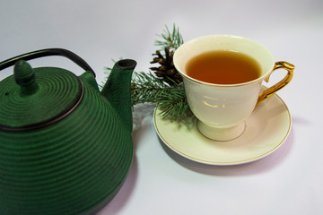 Cast iron green small teapot. White porcelain Cup . White saucer. Christmas tree. white background. The concept of the celebration. relax