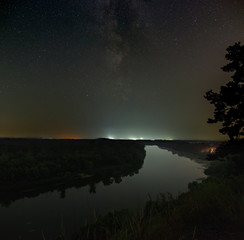 Stars of the Milky Way galaxy in the night sky over the river. Photographed with a long exposure.