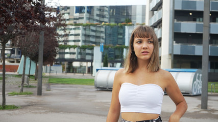 Young pretty woman standing against city buildings while looking away